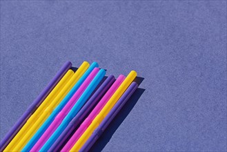 Colored disposable plastic straws on purple background with copy space. Concept of ban on use of plastic tubes in Europe in April 2020