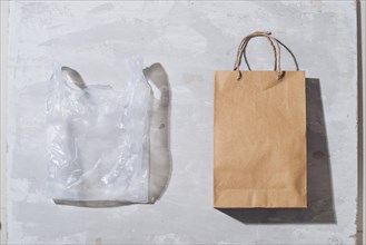 Ugly colorful plastic bag vs brown recyclable eco paper bag. Reduce, Reuse and Recycle concept. Flat lay, view from above, isolated on white