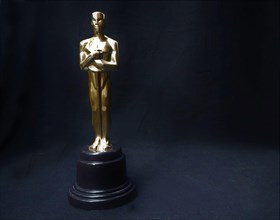 The golden statue of Oscar on a black background. Success and victory concept