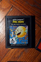 Pacman Atari video game cartridge on wood floor.