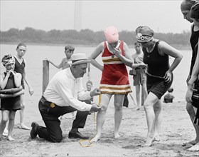 vintage photo of a Sheriff measuring the length of a young girls bathing suit circa 1922.