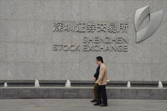 Two men walking by Shenzhen Stock Exchange, China.