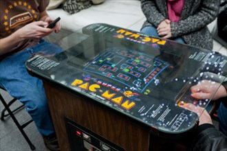 People playing a vintage Pac-Man video arcade game - USA