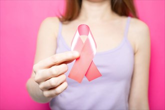The girl is holding a pink ribbon in her hands. Breast Cancer Symbol
