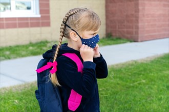 Young student caucasian girl wearing protective cotton mask for school. Return back to school, reopening, new life.