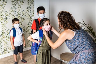 Mother putting face masks on her children before they go to school
