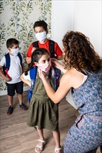 Mother putting face masks on her children before they go to school