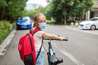 School child wearing face mask during coronavirus pandemic outbreak. Blonde girl going back to school after covid-19 quarantine and lockdown. Kid in