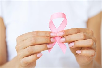 Woman using pink ribbon to support breast cancer cause or AIDS