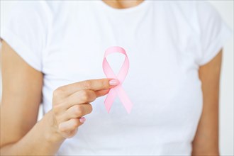Woman using pink ribbon to support breast cancer cause or AIDS