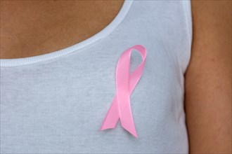 Close up of pink ribbon on woman chest to support breast cancer cause