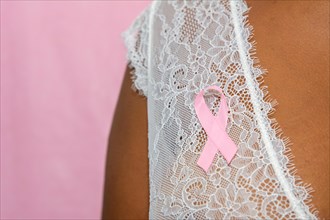 young african american woman with pink ribbon  isolated on pink , breast cancer concept