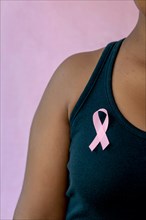 young african american woman with pink ribbon  isolated on pink , breast cancer concept