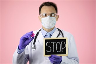 Male lab technician holds covid-19 virus cell and stop message. Global pandemic