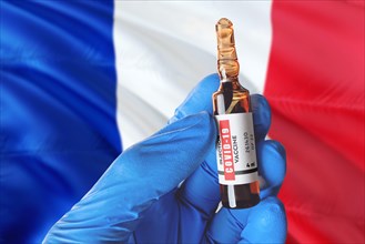France flag with Coronavirus Covid-19 concept. Doctor with blue protection medical gloves holds a vaccine bottle. coronavirus covid 19 vaccine researc