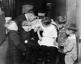 Pediatrician immunizing a little girl while other children are watching