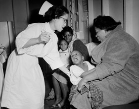 A nurse attempts to give a young child a flu shot in Chicago, ca.1962.