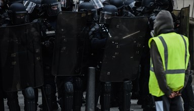 Paris, France - 8 December 2018: Yellow Vests (Gilets jaunes) protester stands in front of French riot police officers during a protests against livin