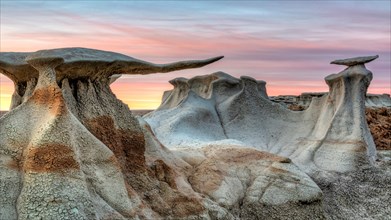 Alien stone wing hoodoos agsainst a pastel sunset in the BIsit/De-Na-Zin WIlderness in New Mexico.