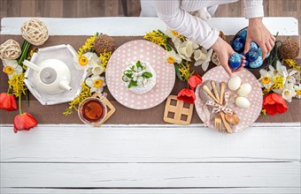 Festive Easter table with homemade Easter cake, tea, flowers and decor details copy space. Family celebration concept.