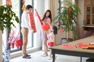Happy family decorating their house for Chinese New Year