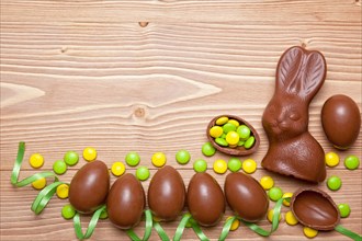 Easter chocolate eggs, bunny and candies on wooden background.