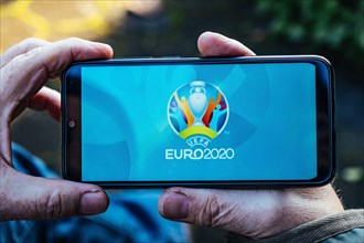 Senior Man is holding a smartphone with logo of UEFA Euro 2020 on screen