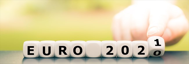 Hand turns dice and changes the expression "Euro 2020" to "Euro 2021".