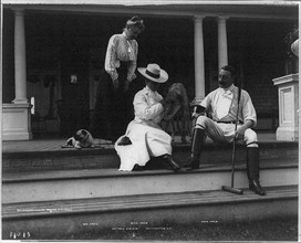 John Drew 1853-1927 full length portrait seated on porch step facing left; with wife Josephine (Baker) and daugher Louisa Drew and 3 dogs at cottage ‘Kyalami‘ Easthampton L.I.;