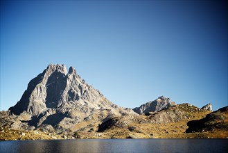 Midi Dossau Peak reflected in Gentau lake. Ossau Valley, Pyrenees National Park, Pyrenees, France.