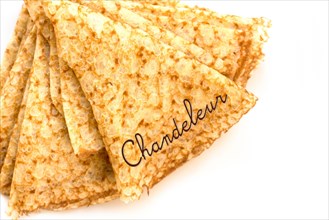 Close up on a stack of folded crepes (french pancakes), text chandeleur, isolated on white background
