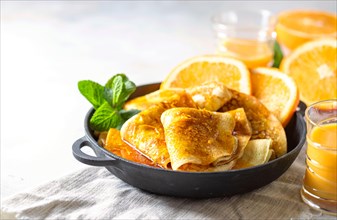 Crepes with Orange Sauce in a cast iron pan. Traditional French crepe Suzette with orange sauce.
