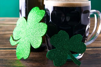 Close-up of two shiny clover leaves on a mug of stout. St. Patrick and stout concept