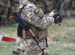 Soldier of Ukraine with assault rifle AK use smartphone. Ukrainian soldier with assault rifle AK.