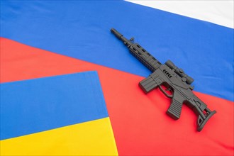 Russian and Ukrainian flags with black painted toy assault rifle. For Ukraine-Russia crisis, Russia Ukraine invasion, tensions / war in Ukraine.