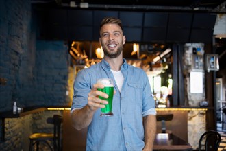 Handsome man holding a beer in a pub for St. Patrick's Day