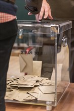 Envelope fallling in a voting box  at a polling station during voting in France