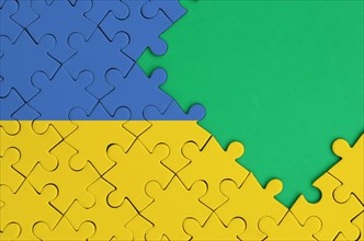 Ukraine flag  is depicted on a completed jigsaw puzzle with free green copy space on the right side.