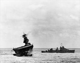 Battle of Midway, June 1942. USS Yorktown (CV-5) being abandoned by her crew after she was hit by two Japanese Type 91 aerial torpedoes, 4 June 1942. USS Balch (DD-363) is standing by at right