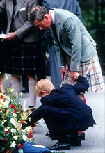 Prince Charles, Prince of Wales, holds the hand of Prince Harry as they view bouquets of flowers left in memory of Diana, Princess of Wales in September 1997 in Balmoral, Scotland.