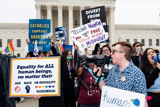 Protesters hold placards reading "Telling women that you won't be free without abortion is mysogyny", "Catholics support abortion access!", and "Equality for ALL human beings, no matter their age, rac...