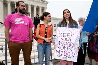 A protester wearing a shirt with words "I stand with Planned Parenthood" stands next to a woman holding a placard reading "Keep your policies off my body" during an abortion related demonstration in f...