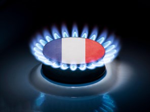 Burning gas burner of a home stove in the middle of which is the flag of the country of France. Gas import and export delivery concept, price per cubi