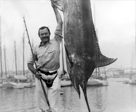Ernest Hemingway (1899-1961) posing with a marlin at Havana Harbor, Cuba, July, 1934.