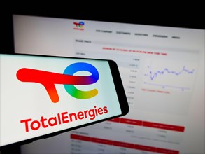 Smartphone with logo of French oil and gas company TotalEnergies SE on screen in front of business website. Focus on center-right of phone display.