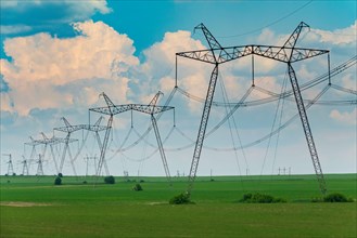 Row of power line support pylons on the countryside field. Energy transition equipment