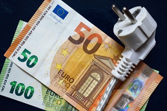 Power plug and euro money, domestic electric cable on European banknotes, top view. Energy crisis in Europe, expensive home electricity price. Concept