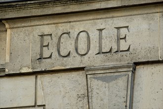 The word ECOLE engraved in stone on the facade of an old building in France