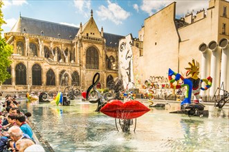tourists taking a break at  the stravinsky fountain close to the centre georges pompidou,  in the background saint merry church