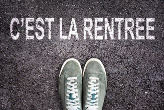 Words C'est la rentree (meaning back to school in french) written on asphalt road with sneakers shoes, high school and college concept